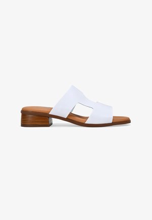 Sandalia deslizante de cuero sintético blanco con punta abierta y diseño cruzado. Tacón bajo de madera y plantilla color marrón. Superficie suave con acentos mínimos.