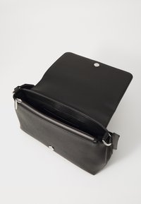 Borsa a tracolla nera in pelle con una superficie liscia, zip argento e chiusura a scatto magnetico. Interno foderato in tessuto, dotato di un ampio scomparto.