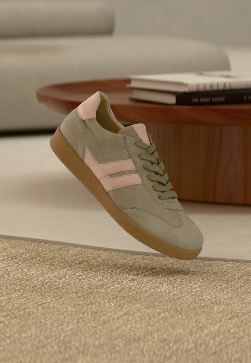 Baskets en daim vert avec accents roses, bout arrondi, design à lacets plats, semelle en caoutchouc et deux bandes horizontales rose clair.