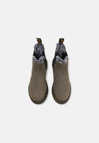 Bottes de cheville en cuir grises avec une doublure en fausse fourrure grise douce, des panneaux latéraux élastiques noirs et des coutures jaunes sur une semelle en caoutchouc noire.