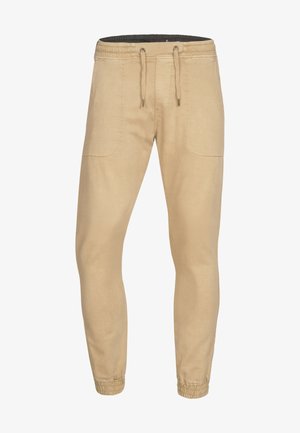 Beige jogger broek met een trekkoord in de taille, elastische manchetten en zijzakken. Gemaakt van zachte, lichtgewicht stof met een gladde textuur.
