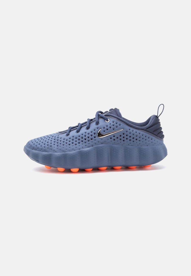 Μονό μπλε αθλητικό παπούτσι Nike με διάτρητο άνω μέρος, μαύρο λογότυπο Nike, χοντρή ενδιάμεση σόλα και πορτοκαλί στρογγυλές πέλτες στην εξωτερική σόλα, σε πλευρική όψη.