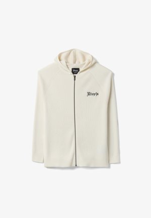 Cremefarbene, gerippte Kapuzenjacke mit Reißverschluss und schwarzem "Utopia"-Text auf der linken Brust sowie angenähter Kapuze, Größe klein.