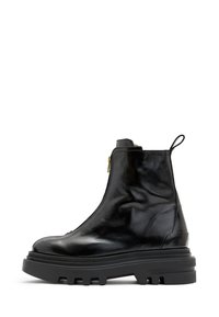 Botas de tobillo de cuero negro con un acabado brillante, cierre de cremallera lateral y suela gruesa de goma negra con un patrón de tracción rugoso.