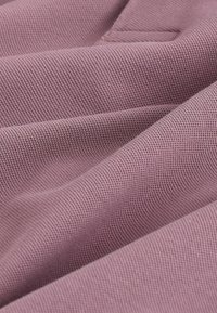 Tissu lilas doux avec un motif de tricot texturé fin, présenté en plis délicats et en détail rapproché.