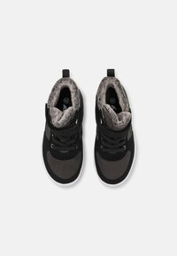 Czarno-szare sneakersy typu high-top z miękkim futrem wewnętrznym, sznurówkami i paskiem na rzep; mają teksturowane panele i białe gumowe podeszwy.