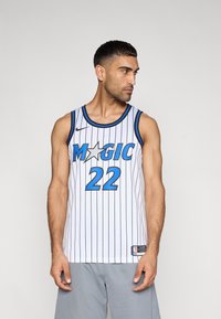 Άσπρη φανέλα μπάσκετ με κάθετες μπλε ρίγες, που φέρει τη λέξη "MAGIC" μπλε, ένα γραφικό αστέρι και τον αριθμό 22 με έντονα μπλε γράμματα.