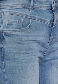 Light blue denim jeans featuring a classic five-pocket design with stitching details, a small watch pocket, and a zip fly opening.