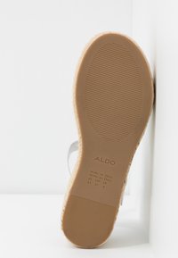 Semelle de sandale avec une surface en caoutchouc texturée de couleur tan. Accentuée par un motif brun clair et marquée avec les informations de marque et de taille.