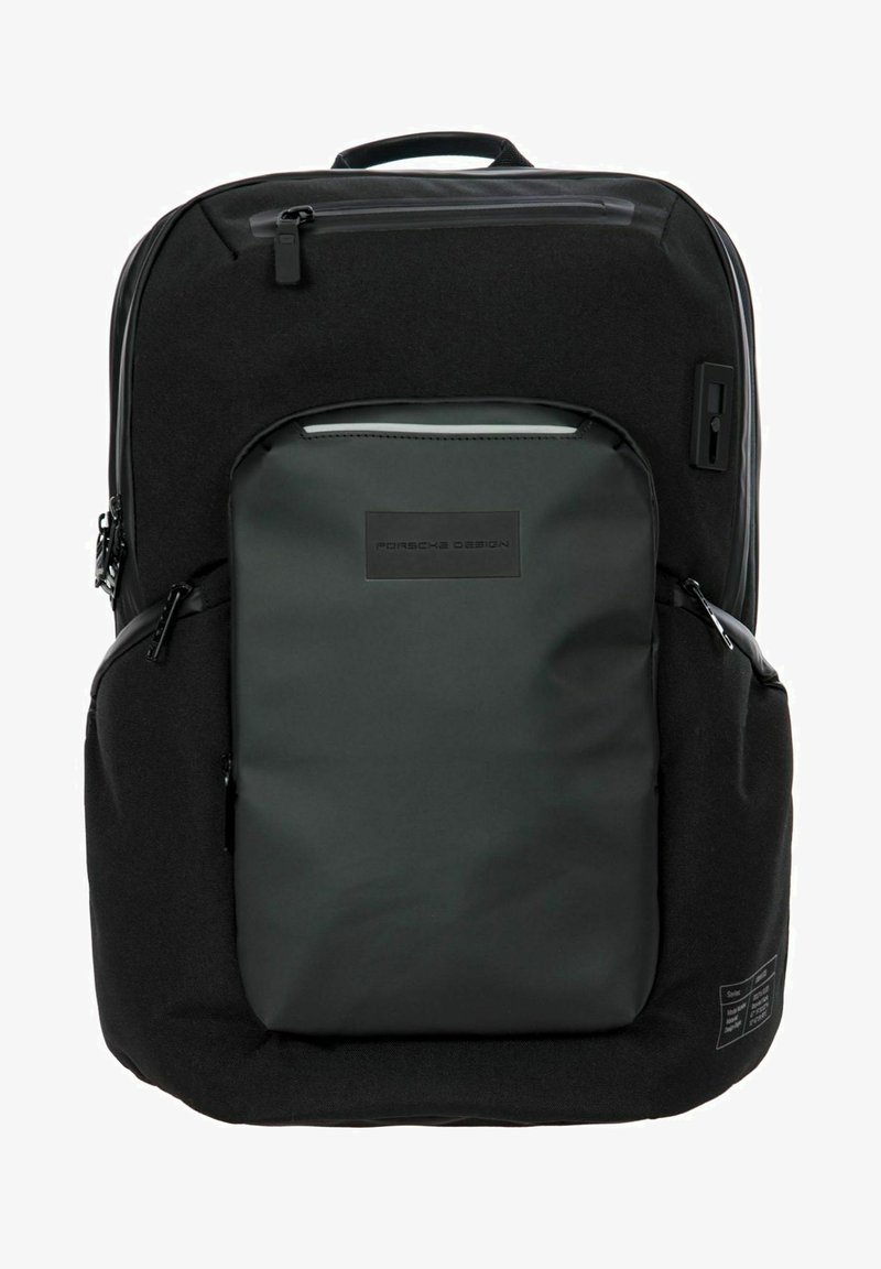 Mochila negra con una textura suave y mate y acentos brillantes. Presenta múltiples bolsillos, cremalleras y un logotipo prominente en la parte frontal.