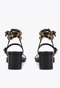 Czarne sandały na obcasie z kwadratowym noskiem i słupkiem. Charakteryzują się dekoracyjnymi złotymi akcentami i krzyżującymi się paskami.