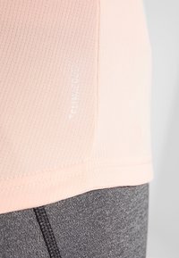 Světlý růžový sportovní tričko s vertikálním žebrováním, s prošitým lemem a textem "CLIMACOOL" v bílé barvě na boku.