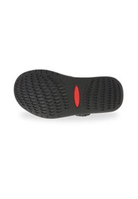 Suela de zapato de goma negra con un patrón texturizado de agarres ovalados y un logotipo rojo en el centro. Presenta un diseño curvado y elementos de tracción.