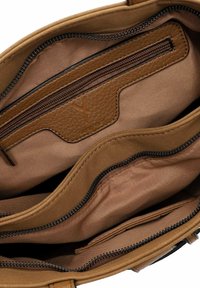 Bruine interieur van een tas met een ritsvak, een gladde textuur en gelaagde vakken. Kenmerkende logo patch nabij de bovenste rits.