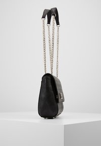 Zwarte lederen handtas met een gegraveerd bloemmotief, zilveren kettingriemen en een gestructureerde silhouet. Heeft een sluiting met een gesp en een gladde textuur.