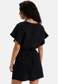 Black crinkle fabric dress with short sleeves, elastic waistband, and a relaxed fit. Features a round neckline and above-knee length.