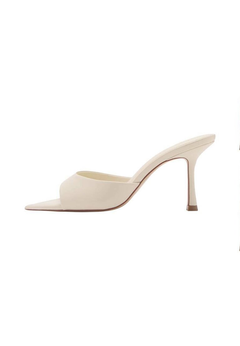Mule beige con tacco alto e punta aperta, realizzate in materiale liscio, con design curva e tacco a stiletto sottile.
