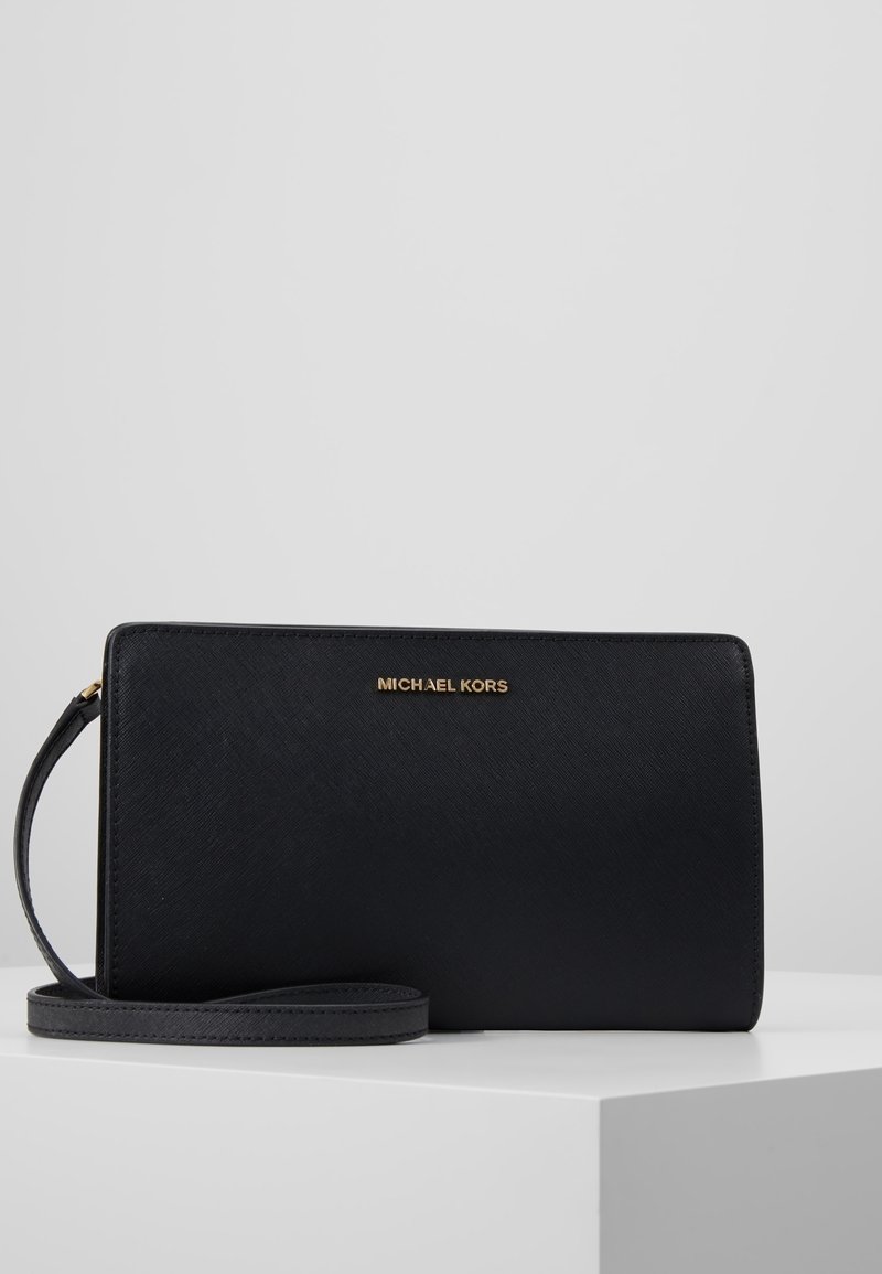 Schwarze Michael Kors Geldbörse mit strukturierter Oberfläche, goldfarbenem Logo und abnehmbarem Riemen. Rechteckige Form, schlankes Design mit minimaler Hardware.