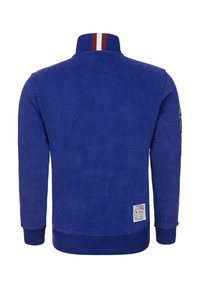 Modrá fleecová bunda s vysokým límcem s červenými a bílými pruhy, žebrovanými manžetami a štítkem na spodní levé straně.