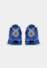 Chaussures de sport bleues avec une tige en mesh, des accents gris et une semelle en caoutchouc texturée dotée d'un design de rembourrage distinctif.
