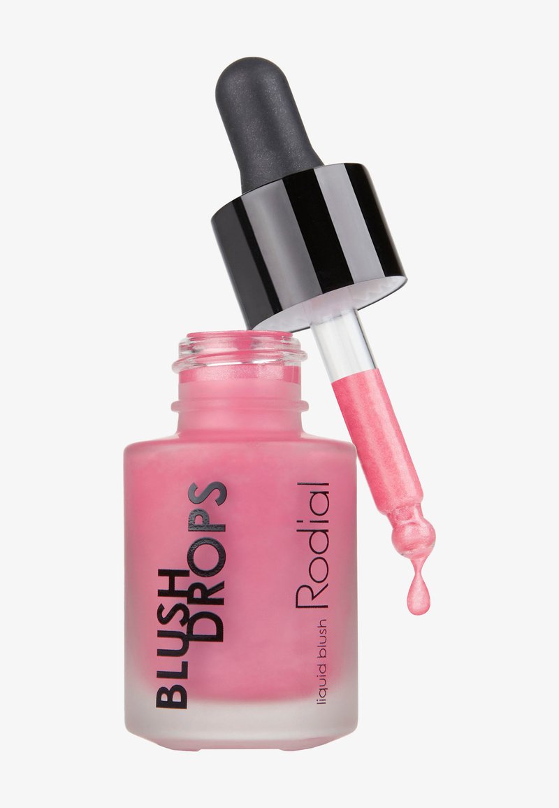 Flacon de blush liquide rose étiqueté "BLUSH DROPS Rodial" avec une pipette noire libérant une goutte de produit.