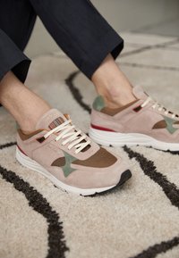 Sneakers med en rosa mockayttermantel, meshpaneler, gröna accenter, texturerad sula och off-white snören. Designade med en kontrasterande röd häl.