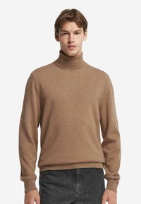 Brun polotröja i mjukt stickat material. Har långa ärmar och ribbade ärmslut och fåll, med en slät textur.