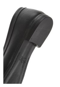 Scarpa in pelle nera con punta arrotondata. Presenta una texture liscia, cuciture lungo i lati e un tacco in gomma leggermente elevato.