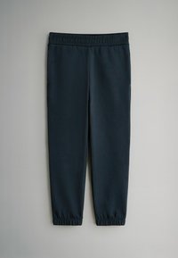 Pantalones jogger de un azul marino oscuro hechos de tela suave, con cintura elástica, piernas entalladas y puños elásticos en los tobillos. Sin bolsillos visibles.