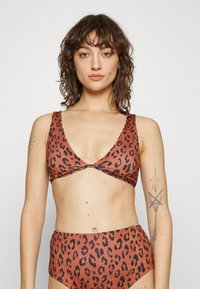 Leopárdmintás bikini felső mély V-nyakkivágással, barna és fekete színkombinációval, texturált anyagból, széles pántokkal a támogatás érdekében.