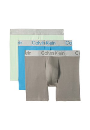 Trois paires de boxers homme en gris, bleu et vert clair avec des ceintures gris clair et le logo Calvin Klein.