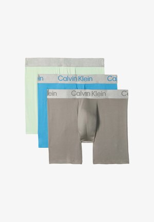 Trois paires de boxers homme en gris, bleu et vert clair avec des ceintures gris clair et le logo Calvin Klein.