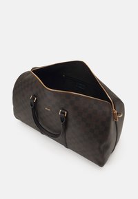 Bruine geruite weekendtas met zwarte leren accenten en gouden hardware. Voorzien van een ritsluiting en een ruime binnenkant.