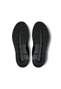 Schwarze Sportschuhsohlen aus strukturiertem Gummi, mit Rillen für Traktion und einem zentralen Design für Flexibilität.