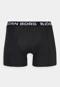 Schwarze Boxershorts aus elastischem Material. Mit Weißem Logo am Bund und glatter Textur. Kurzes Beindesign mit minimaler Naht.