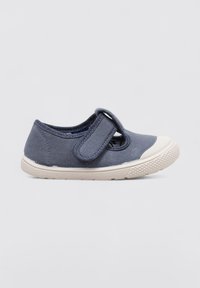 Zapatilla de lona azul con punta redonda y suela de goma blanca. Cuenta con una cinta de velcro en el empeine para un ajuste seguro. Tejido texturizado.