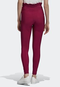 Tight högmidjade leggings i en livlig magenta färg, med en volangmidja och mjukt, stretchigt tyg. Matchat med vita skor.