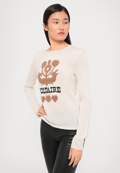 Krämen långärmad tröja med ett brunt blommönster och hjärtan, med ordet "VOLTAIRE" i svart nedanför. Mjuk textur, åtsittande design.