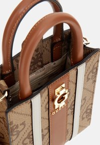 Bolso de lona marrón con un patrón, dos asas redondeadas, herrajes dorados y acento de logo. Presenta rayas verticales blancas contrastantes.