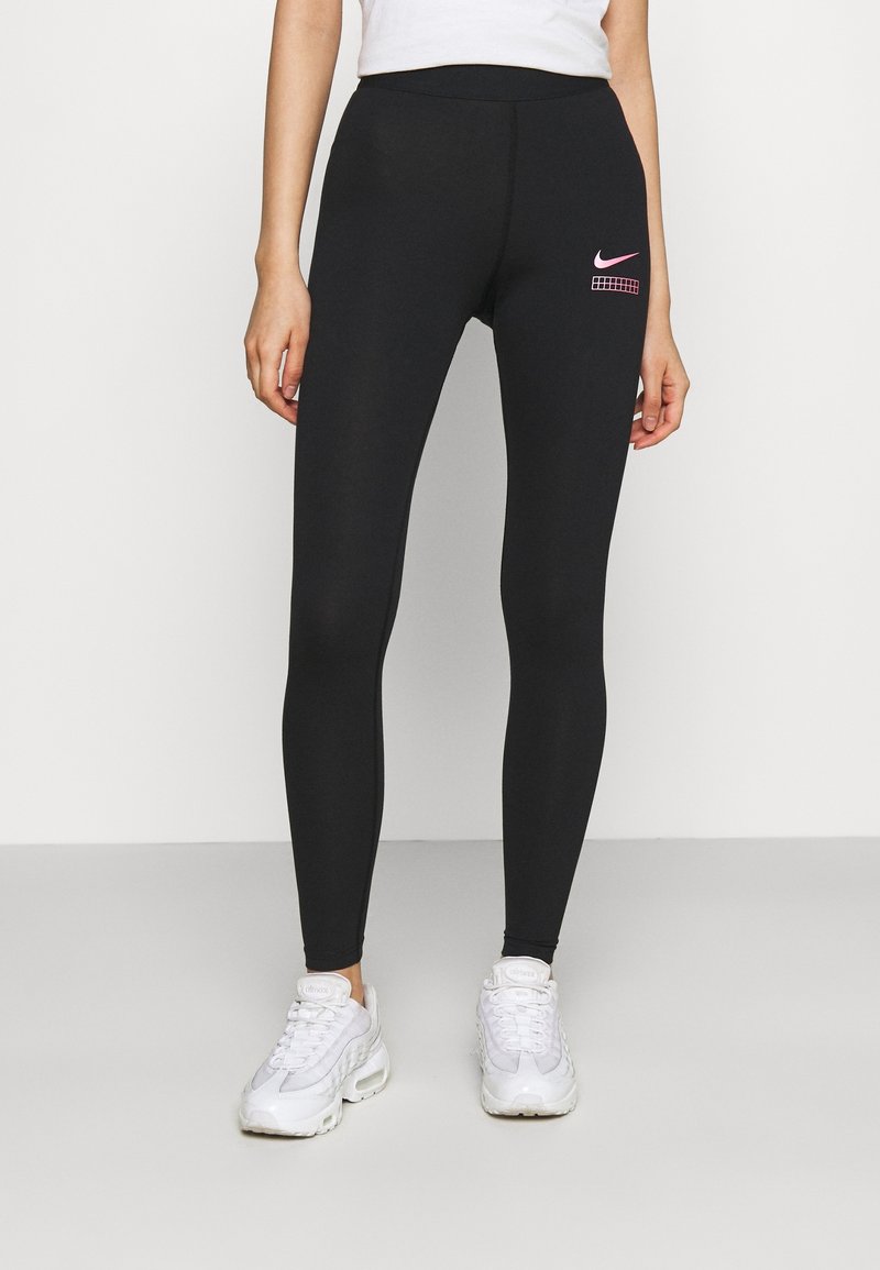 Svarta leggings i elastiskt material, med en rosa Nike-logotyp på höften. Slät yta, figurnära design och ankellång klipp.