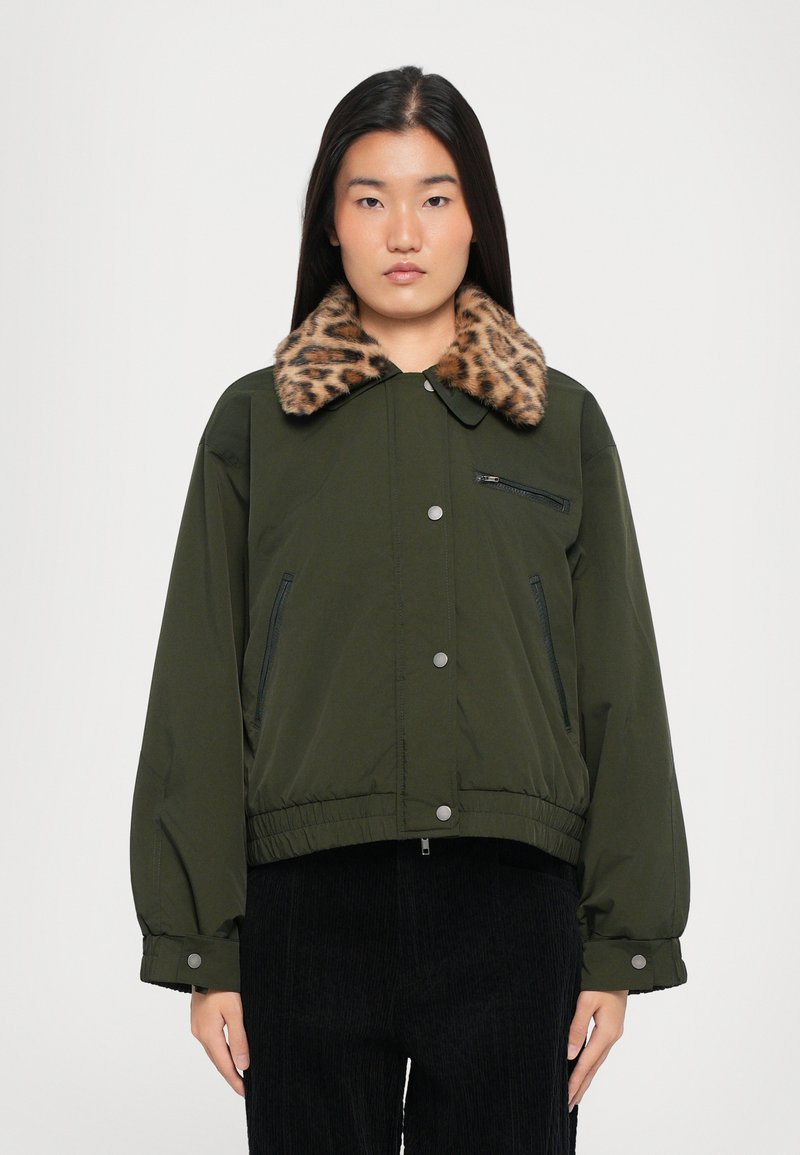 Alyvuogių spalvos bombenjakas su leopardų rašto dirbtinio kailio apykakle, užtrauktuku užsegamu krūtinės kišenė, šoninėmis kišenėmis ir elastingu hemu bei rankogaliais.