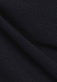 Tessuto blu scuro con una trama a maglia testurizzata, che mostra dettagli a coste e intrecciati. Il materiale appare morbido e denso, con sottili variazioni di luce.