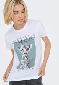 Camiseta de algodón blanca con un gráfico de una jirafa usando gafas de sol, con el texto "SAFARI" y "VIVIENDO LA ALTA VIDA" en un diseño colorido.