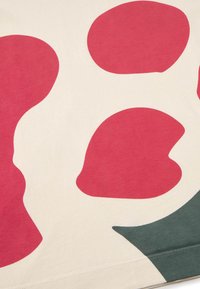 Beige bomullstyg med stora röda former och ett mörkgrönt böjt designelement. Mjuk struktur, tydlig färgkontrast och minimalistisk design.