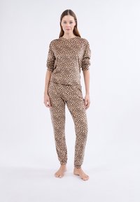 Souprava domácího oblečení s leopardím vzorem vyrobená z měkké látky, obsahující volný top s manžetovými rukávy a odpovídající zúžené kalhoty.