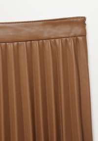 Jupe plissée marron en faux cuir avec une taille ajustée et une fermeture éclair latérale sur fond blanc.