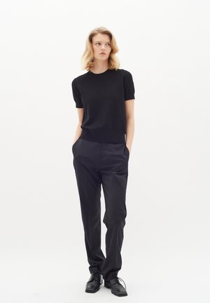 Black short-sleeve top paired with black tailored trousers and shiny black shoes. Simple, fitted design with a smooth texture.