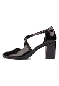 Talons en cuir verni noir avec un bout arrondi, une sangle entrecroisée et un design de talon bloc. Fini brillant mettant en valeur la texture. Détail de boucle réglable.