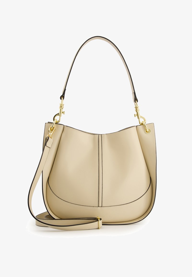 Sac à épaule en cuir beige avec un haut incurvé, des coutures surélevées, des bords noirs et une bandoulière amovible. Des accents en métal doré ajoutent une touche de détail.