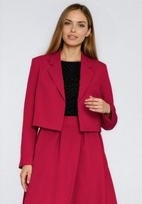 Fuksjowa krótka marynarka z klapami z wycięciami, długimi rękawami i dopasowanym krojem, zestawiona z dopasowanym czarnym topem w delikatne groszki.